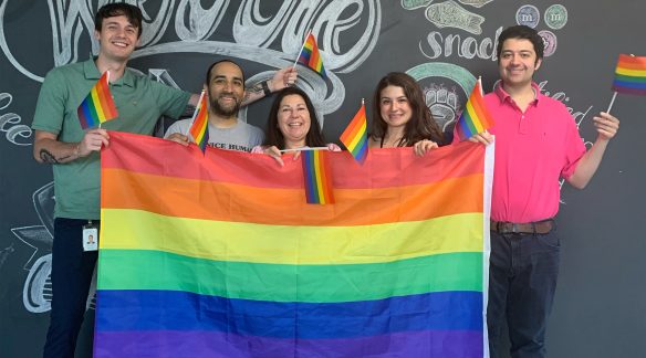 Austin, Kofi, Janet, Faith and Jordan holding a large Pride flag.