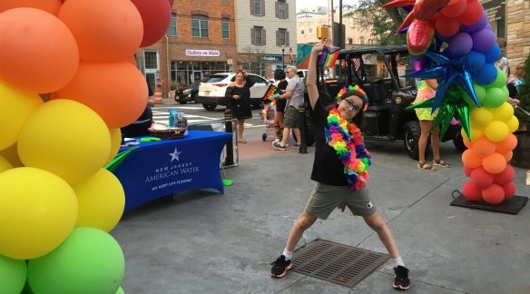 Juniper under a balloon Pride arch during the day.