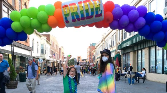 Juniper and Miles under a Pride balloon arch.