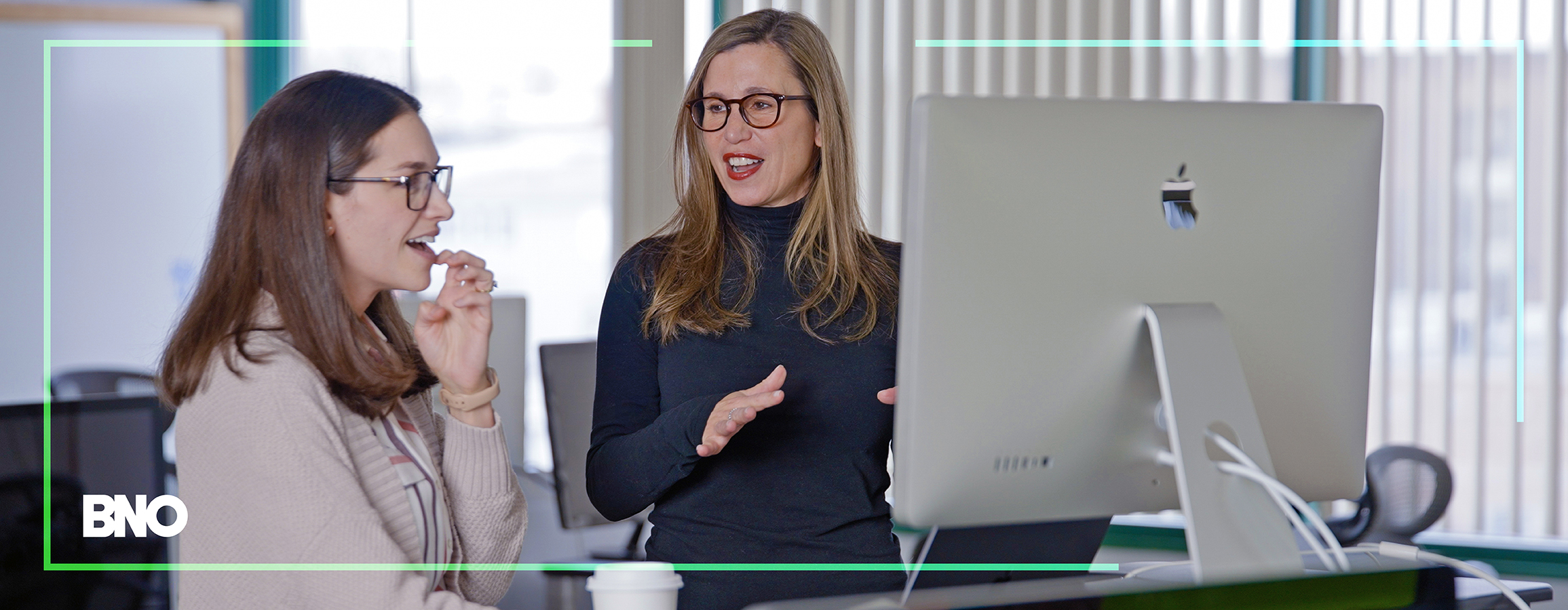 Two BNO employees reviewing a project on a monitor.
